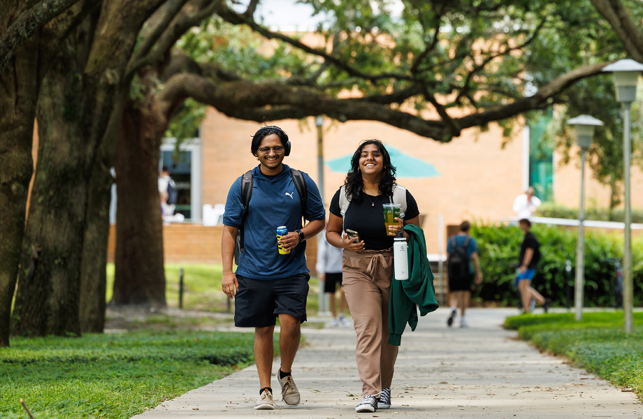 Pair of students walking under tree