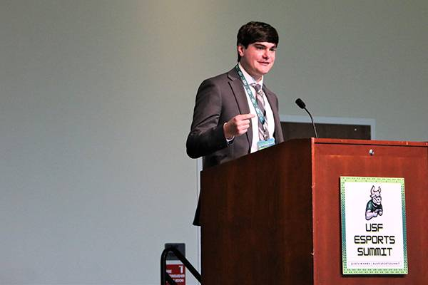 Gaming content creator Jeremiah Woodward stands behind a podium and speaks to an audience