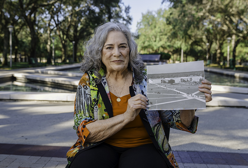 Jeanne Dyer, member of USF's charter class, holds up a photo of USF from the 1960s when she attended classes