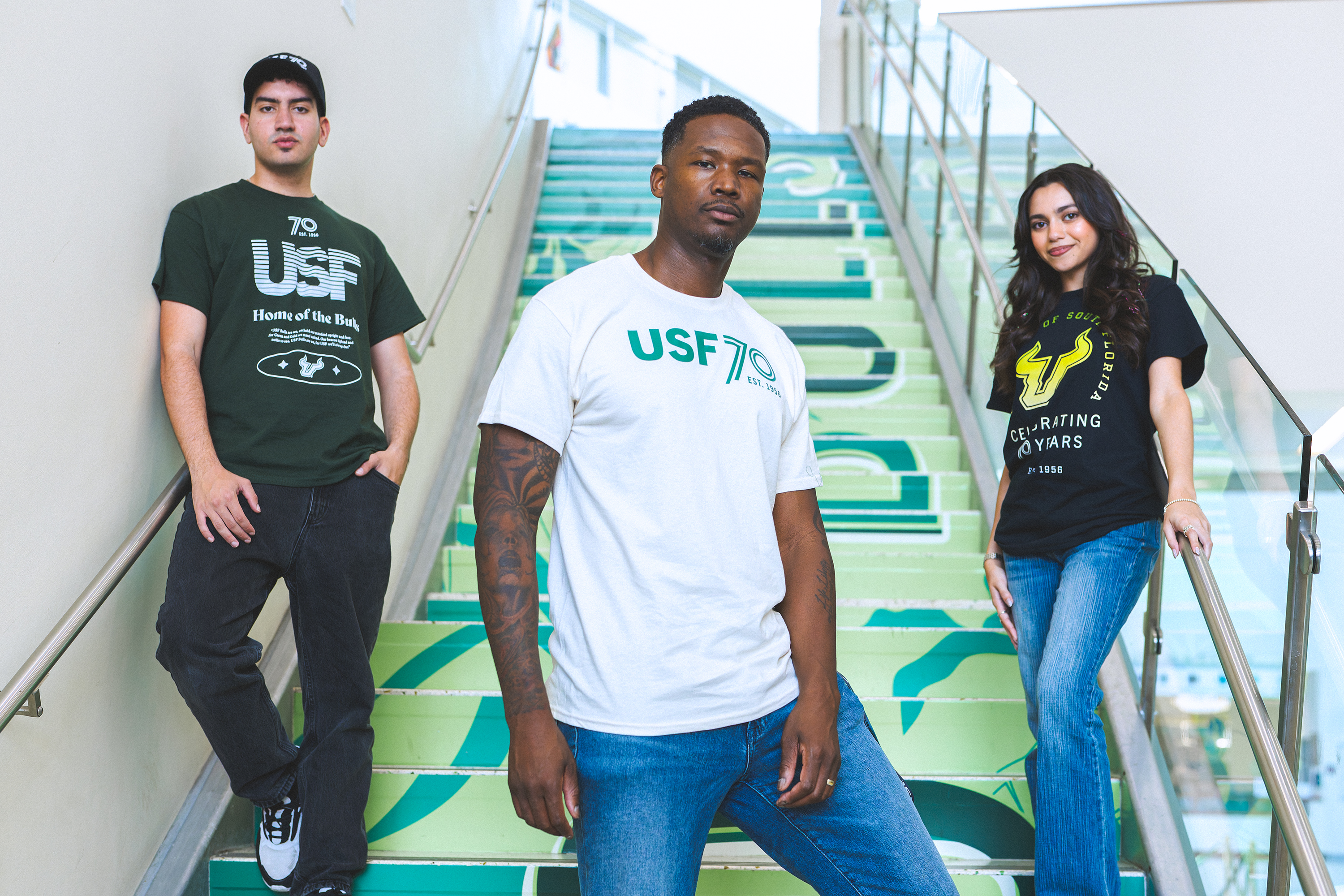 Students and staff members showcasing three USF70 shirts on campus