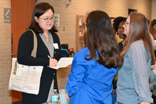 Student speaking with two women during community fair.