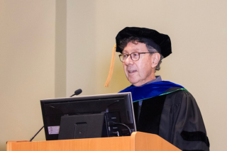 Dr. Rick Weinberg addressing graduates while at the podium.