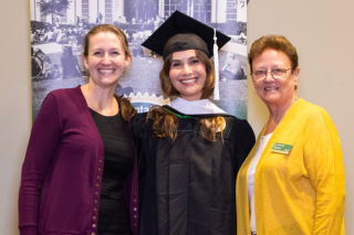 graduate smiling at camera with faculty member and dean of the college on either side.
