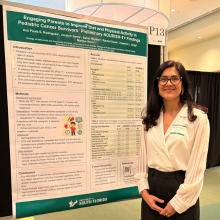 woman standing in front of research poster in conference ballroom