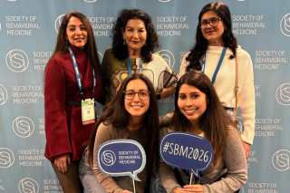 group of 5 ladies with a backdrop for society of behavioral medicine