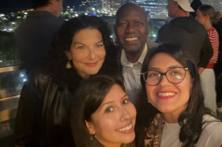 group of four individuals taking a selfie with a cityscape in background
