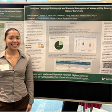 young woman smiling, standing in front of research poster.