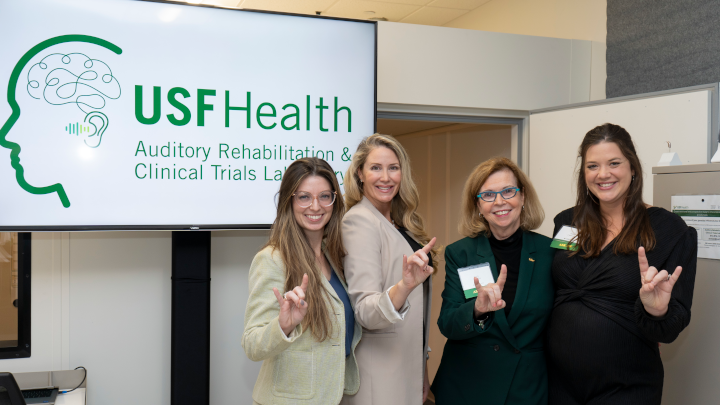 ARCT Team in front of a board reading "USF Health Auditory Rehabilitation & Clinical Trials Laboratory"