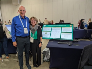 Jennifer Venne and Howard Goldstien in front of a digital presentation poster