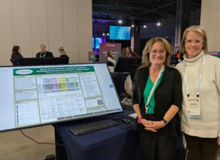 Lindsey Peters-Sanders and Jennifer Venne standing in front of a digial presentation poster