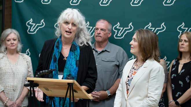 Joan Reid, USF professor of criminology and director of the TIP Lab, speaks behind a podium
