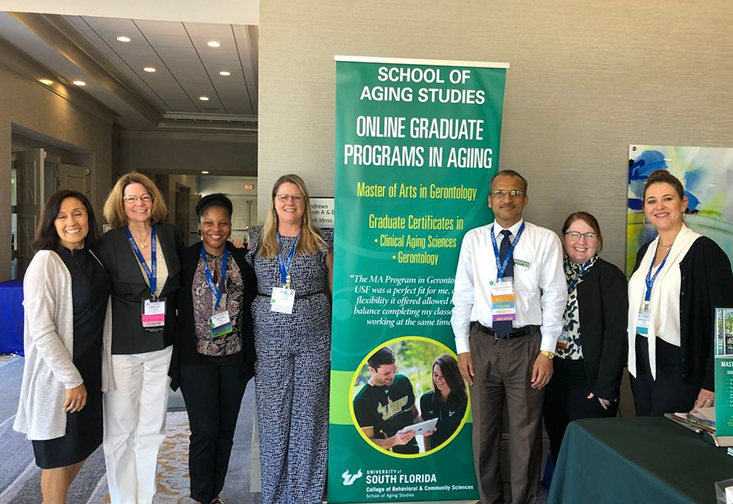 A group of aging studies students, faculty, and staff gathered at the USF School of Aging Studies informational booth at the Southern Gerontological Society's Annual Meeting and Conference.