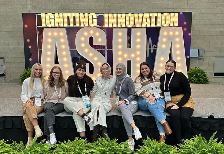 CSD students smile for a picture in front of ASHA sign