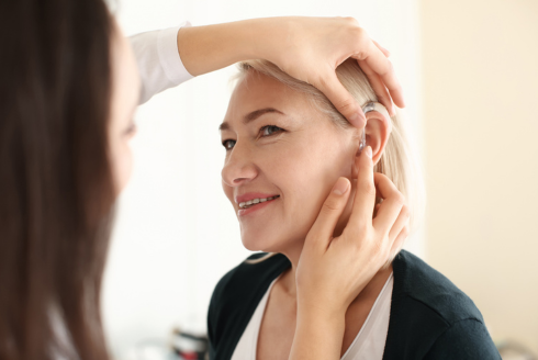 Woman smiles as hearing aid is applied