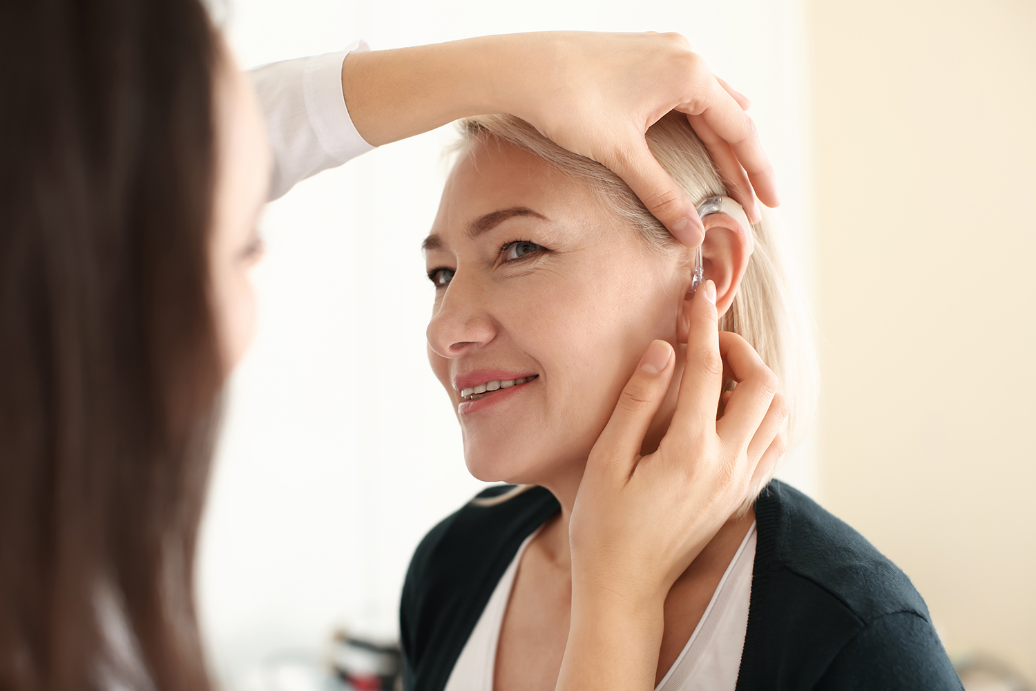 Woman smiles as hearing aid is applied