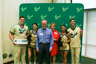 Max celebrates the Department of Criminology's 50th anniversary with his wife Debbie and USF cheerleaders