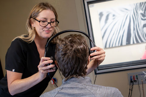 Michelle Arnold places headphones on a male patient facing her