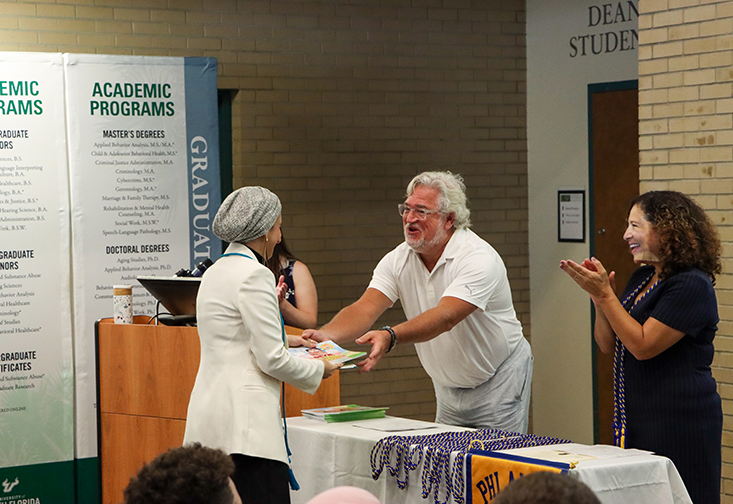 Chris Groeber hands graduate a book