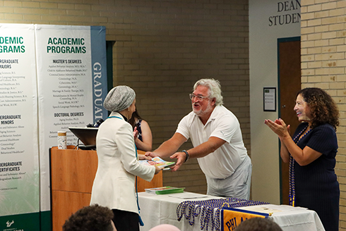 Chris Groeber hands graduate a book