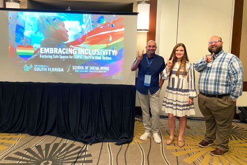 Presenters stand in front of their embracing inclusivity power point presentation.