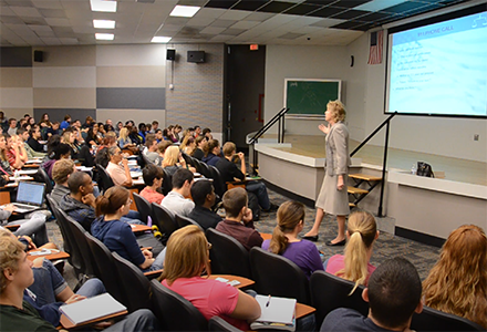 Heide teaching in an auditorium full of students