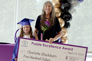 Charlotte Blackburn and HIPPY graduate hold a $500 check