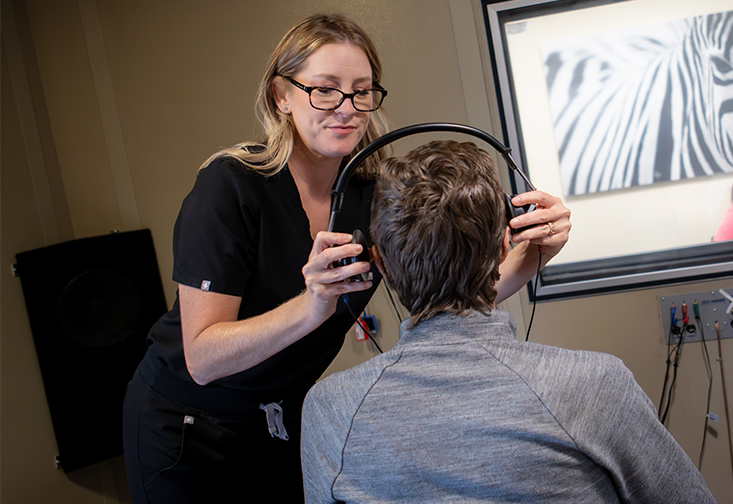 Michelle Arnold places headphones on a male patient facing her