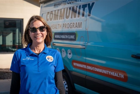 Angela Sciarrone stands in front of a van that says Manatee County Community Health Program 