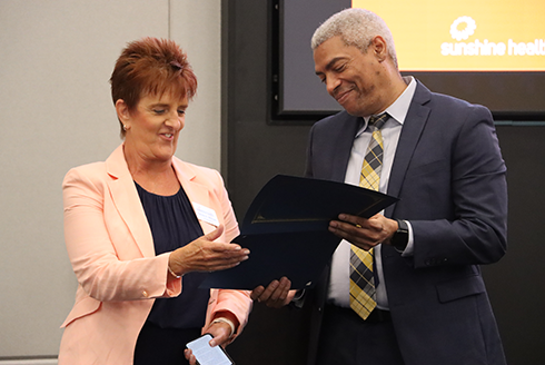 Chris Simmons presents Carole Maytas, vice president of operations for Sunshine Health, with an award at at the school's Social Work Month Celebration hosted at Centene's headquarters