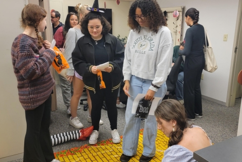 Students wearing costumes going through the yellow brick road in a classroom trying to go through a scavenger hunt.