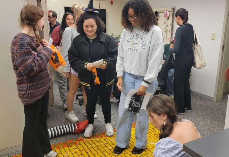 Students wearing costumes going through the yellow brick road in a classroom trying to go through a scavenger hunt.