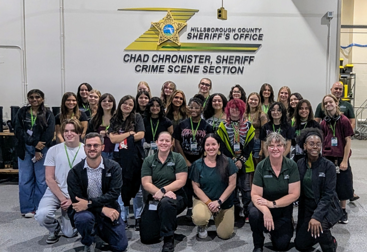High school student camp participants taking a group photo in front of the Hillsborough County Sheriff's Office crime scene section sign