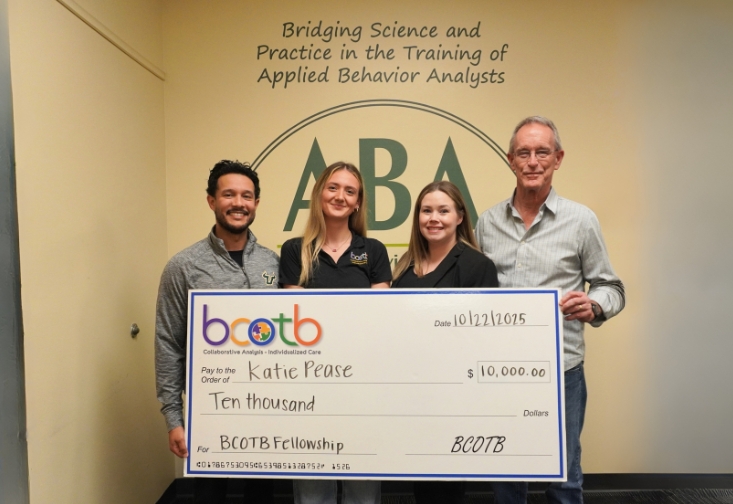 Anthony Concepcion, Katie Pease, Heatherann Tenowich, and Ray Miltenberger holding the ten thousand dollar check in front of the ABA wall art