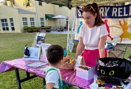 Liz Burke with a child helping them pick out one of the activites on the table to choose from