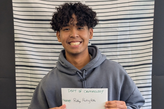 A student poses for a photo in front of the mock mug shot prop at the Week of Welcome event.