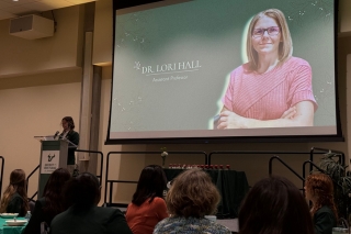 Lily Curwick at the podium with Lori Hall's photo projected on a screen