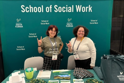Valentina (V.) Arcilla and Valentina Zambrano-Bastidas in front of a school of social work backdrop and a table filled with materials