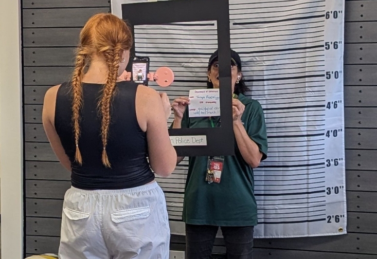 Students take photos in front of mug shot wall