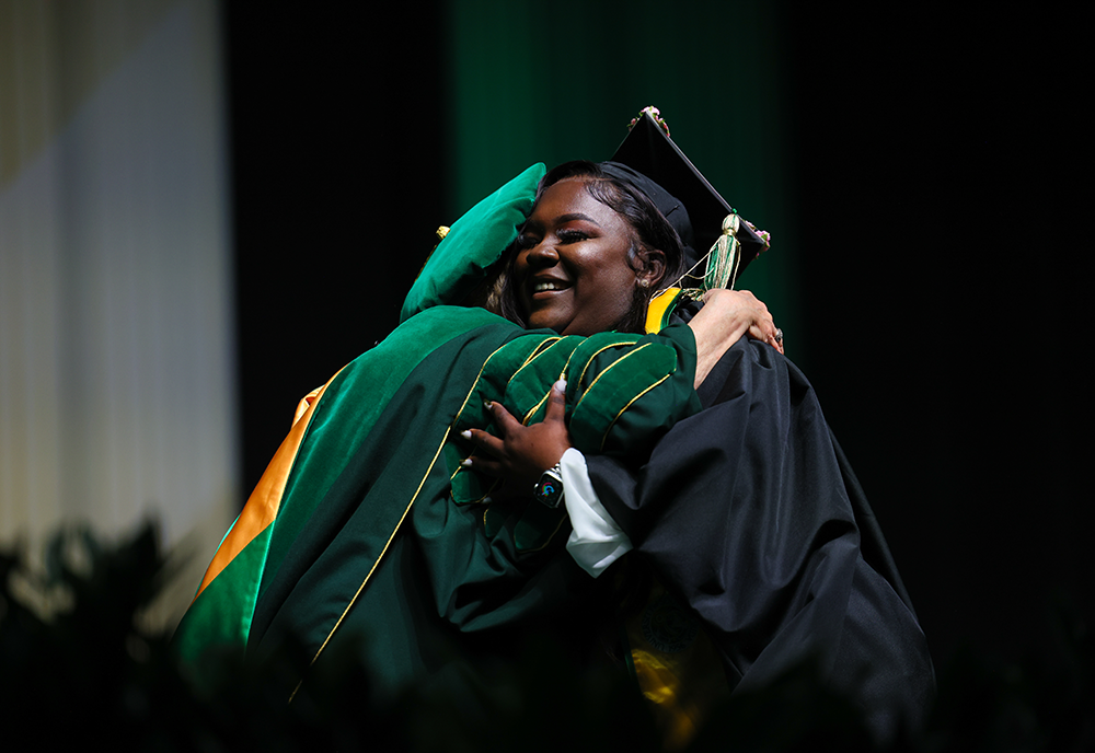 A graduate hugging a faculty member