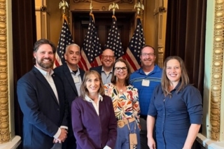 Angela Sciarrone in a group photo in front of the American Flag