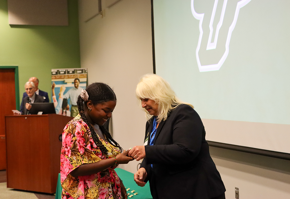 Graduate student receives pin from Nickie Zenn 