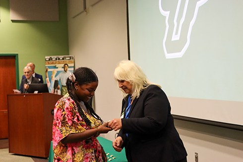 Graduate student receives pin from Nickie Zenn 
