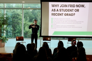 Kyle Volling standing on a stage and speaking to a crowd 