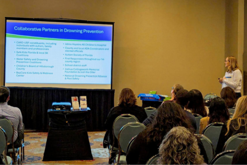 Christine Rover presenting to an audience with a presentation slide on the screen