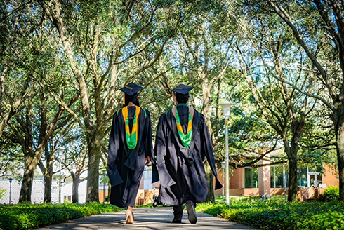Two graduating students stand side by side, making the USF 