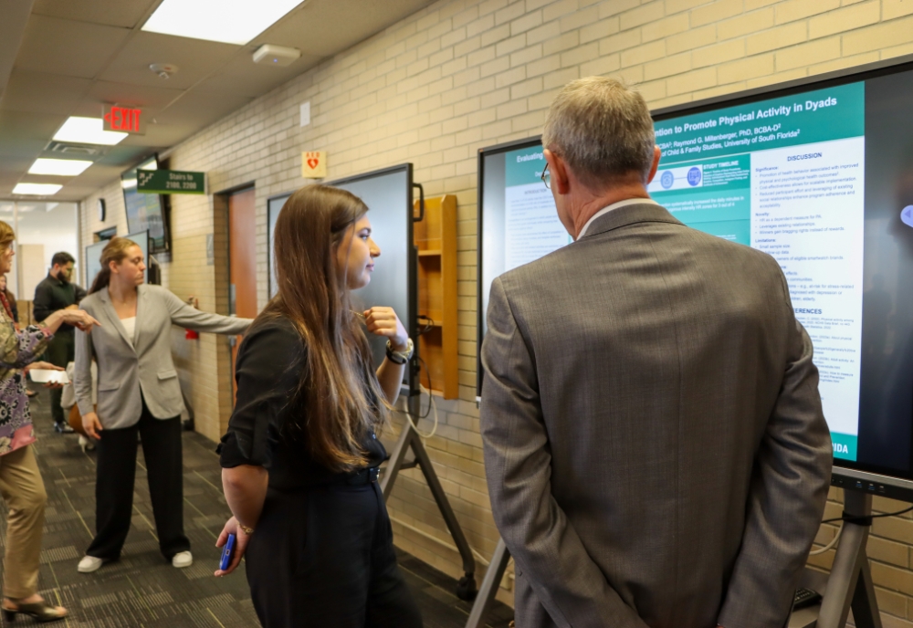 Students present their research project to attendees on an electronic screen