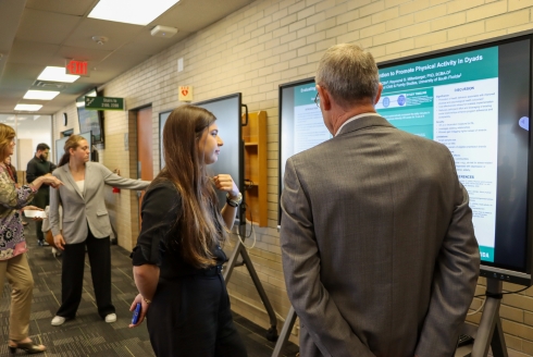 Students present their research project to attendees on an electronic screen