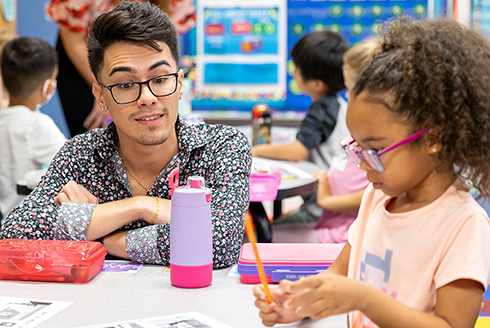 Student teacher working withe elementary age student in classroom