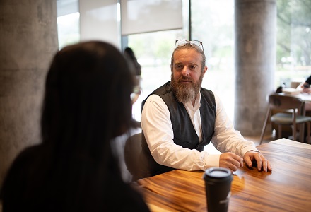 Two people talking while seated at a table.