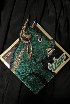 A bejeweled green and gold mosaic of Rocky the Bull on a grad cap